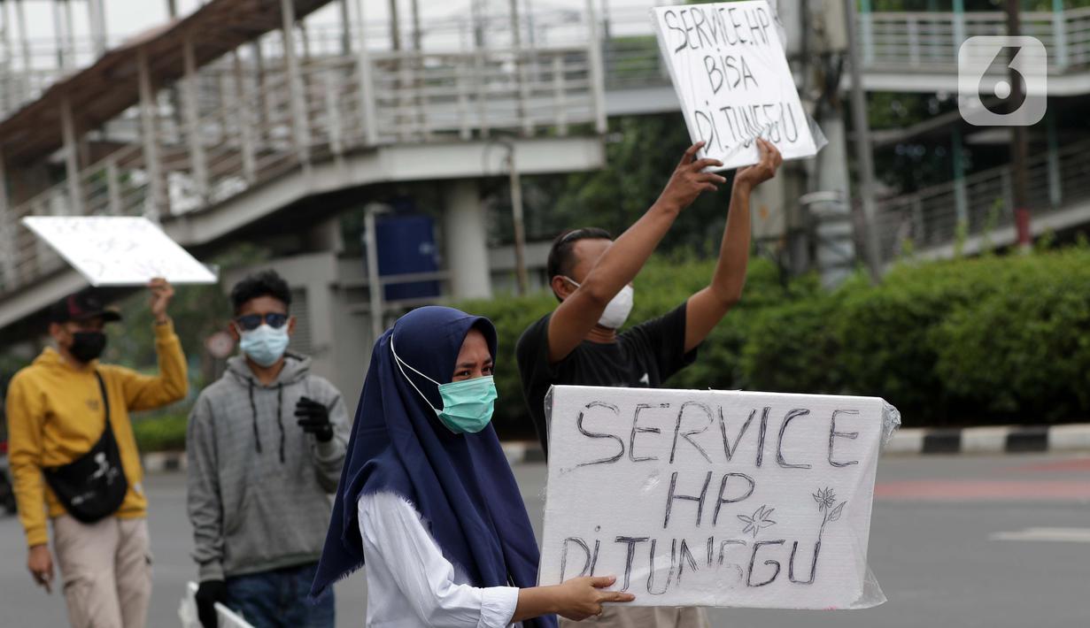 Penjual jasa perbaikan telepon genggam menawarkan jasa di pinggir jalan Mayjen Sutoyo depan Mall Pusat Grosir Cililitan (PGC), Jakarta, Rabu (14/7/2021). Imbas dari penutupan Mall PGC selama PPKM Darurat Jawa-Bali, mereka terpaksa menawarkan jasa di pinggir jalan. (Liputan6.com/Helmi Fithriansyah)