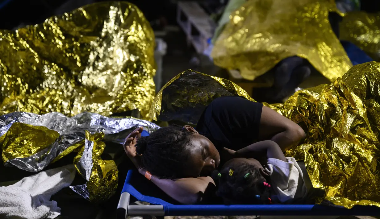 Seorang perempuan dan seorang anak tidur di luar pusat penerimaan migran Lampedusa, Sisilia, Kamis pagi, 14 September 2023. (AP Photo/Valeria Ferraro)