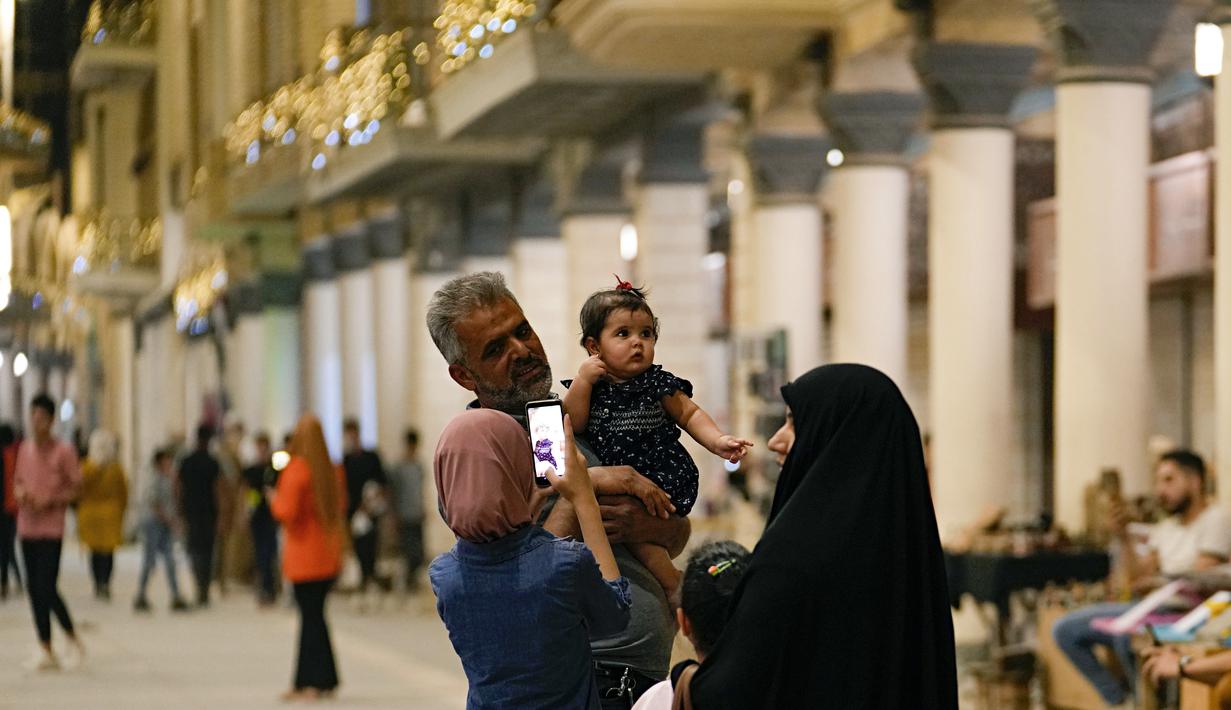 Warga Irak berfoto di Jalan Mutanabi Baghdad, Irak (18/5/2022). Jalan Al-Mutanabbi merupakan pusat jual beli buku yang bersejarah di Baghdad, sebuah jalan yang dipenuhi toko-toko buku dan lapak-lapak penjual buku. (AP Photo/Hadi Mizban)