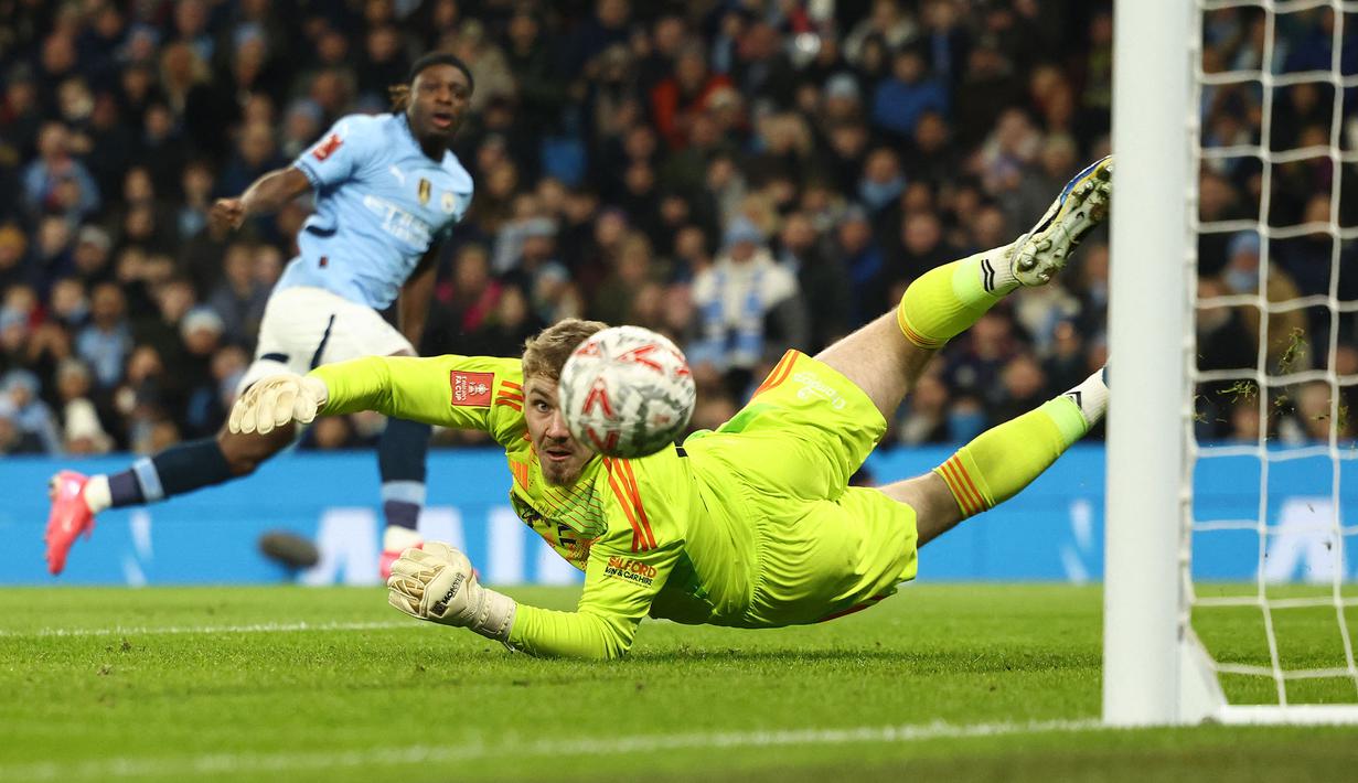 Kiper Salford City, Matt Young (kanan) gagal menghalau bola tendangan pemain Manchester City, Jeremy Doku pada laga lanjutan Piala FA 2024/2025 di Etihad Stadium, Manchester, Inggris, Minggu (12/01/2025). (AFP/Darren Staples)