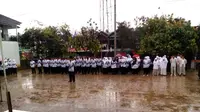 Upacara memperingati HUT PGRI dan Hari Guru Nasional di bawah guyuran hujan. Foto: (Jayadi Supriadin/Liputan6.com)