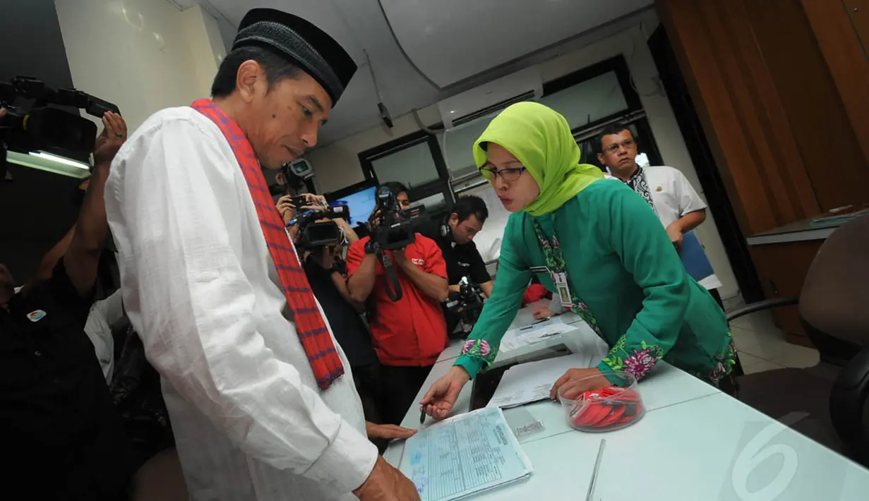 Jokowi saat sedang bertanya kepada petugas penjaga loket pelayanan Kecamatan Pasar Minggu tentang proses pembuatan akte kelahiran‎ dan waktu yang diperlukan, Jumat (23/5/14). (Liputan6.com/Herman Zakharia)