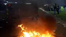 Petugas berpakaian preman berdiri dekat kendaraan polisi yang rusak dalam kerusuhan pada pertandingan sepak bola antara Arema Vs Persebaya di Stadion Kanjuruhan, Malang, Jawa Timur, 1 Oktober 2022. Kapolda Jawa Timur Irjen Pol Nico Afinta menjelaskan sebanyak 34 orang dilaporkan meninggal dunia di Stadion Kanjuruhan, Kabupaten Malang, sementara sisanya meninggal saat mendapatkan pertolongan di sejumlah rumah sakit setempat. (AP Photo/Yudha Prabowo)