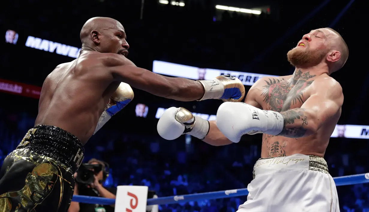 Floyd Mayweather melepaskan pukulan ke wajah Conor McGregor dalam pertandingan tinju super kelas welter di Las Vegas (26/8). Mayweather menang TKO di ronde kesepuluh. (AP Photo/Isaac Brekken)