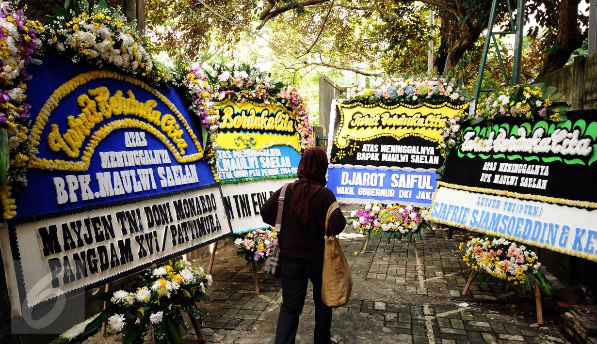 Pelayat melintasi karangan bunga duka cita wafatnya Maulwi Saelan di Al Azhar Syifa Budi, Jakarta, Selasa (11/10). Maulwi Saelan mantan penjaga gawang Timnas Indonesia era 50-60 dan mantan ajudan Presiden Soekarno. (Liputan6.com/Helmi Fithriansyah)