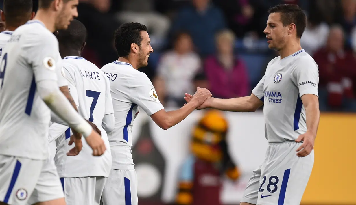 Pemain Chelsea, Pedro dan Cesar Azpilicueta merayakan gol pertama timnya ke gawang Burnledalam lanjutan Premier League di Turf Moor, Jumat (20/4). Gol bunuh diri Kevin Long dan tembakan Victor Moses memenangkan Chelsea dengan skor 2-1. (OLI SCARFF/AFP)