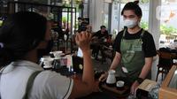 Pekerja kafe penyandang tuna rungu atau tuli menggunakan bahasa isyarat di Kafe Serona Bintaro, Tangerang Selatan, Kamis (7/10/2021). Kafe Serona merupakan tempat makan yang mempekerjakan 8 penyandang tuna rungu sebagai tempat berintraksi teman tuli dan juga masyarakat umum (merdeka.com/Arie Basuki)