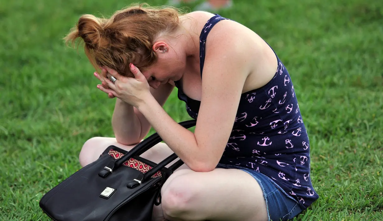 Cristina Gilbert berdoa untuk korban penembakan di Pulse, klub malam khusus kaum gay di Orlando, Florida, AS, Minggu (12/6). Sebelumnya, seorang pria bersenjata menyandera sejumlah orang setelah menembaki klub gay tersebut. (REUTERS/Steve Nesius)