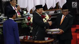 Ketua DPR Bambang Soesatyo (tengah) menyerahkan RUU tentang APBN TA 2020 beserta Nota Keuangan dan pendukungnya kepada Ketua DPD Oesman Sapta Odang dalam Sidang Paripurna di Gedung DPR, Jakarta, Jumat (16/8/2019). DPR akan membahas RAPBN 2020 untuk disahkan menjadi UU. (Liputan6.com/JohanTallo)