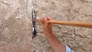 Pekerja dilengkapi dengan tongkat panjang membersihkan catatan yang dijejalkan di celah-celah Tembok Barat, tempat doa paling suci Yudaisme di Kota Tua Yerusalem pada 20 September 2022. (AFP/Ahmad Gharabli)