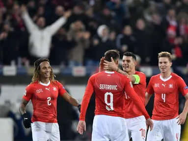 Haris Saferovic dan Granit Xhaka merayakan gol pertama timnas Swiss pada laga Nations League yang berlangsung di stadion Swiss porarena, Senin (19/11). Timnas Swiss menang 5-2. (AFP/Fabrice Coffrini)