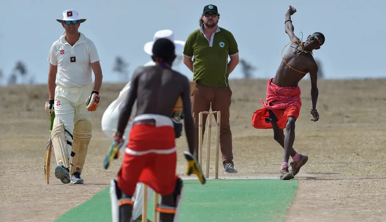 Seorang pria dari suku Maasai melempar bola saat pertandingan amal kriket di kaki Gunung Kenya (18/6). Pertandingan amal ini digelar untuk meningkatkan kesadaran akan nasib badak putih yang hampir punah. (AFP Phoo/Tony Karumba)