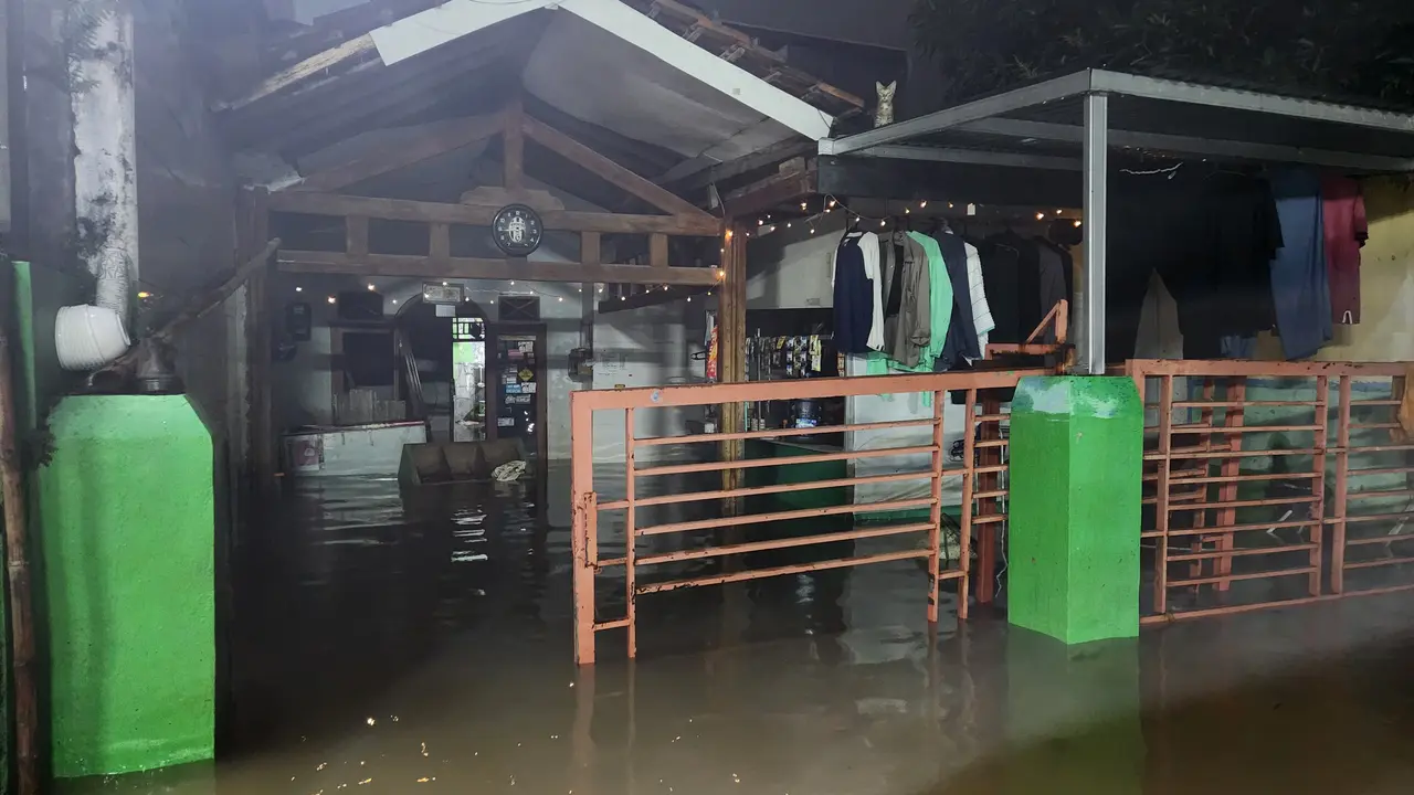 Banjir di Perumahan Sawangan Asri akibat luapan air Kali Pesanggrahan, Sawangan, Depok, Minggu malam (9/3/2025). (Liputan6.com/Dicky Agung Prihanto)
