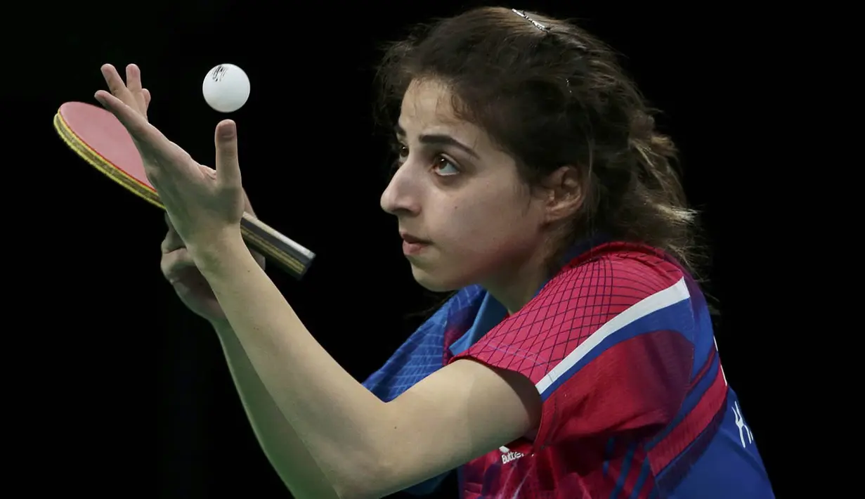 Petenis meja Suriah, Heba Alejji, serius saat akan memukul bola pada laga Olimpiade 2016. Dirinya gagal melangkah jauh karena dikalahkan oleh atlet Meksiko, Yadira Silva, pada babak penyisihan. (Reuters/Alkis Konstantinidis)