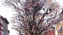 Pengunjung berdiri di depan pohon robinia berhias 10.000 telur paskah warna-warni di Saalfeld, Jerman, Jumat (30/3). Pohon Paskah, merupakan tradisi lain yang berumur berabad-abad dan dibuat dari pohon atau semak kecil yang masih hidup. (AP/Jens Meyer)