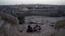 Warga Palestina berkumpul untuk berbuka puasa selama bulan suci Ramadan dengan latar belakang Kota Tua Yerusalem dan kompleks Masjid al-Aqsa yang ditutup selama krisis pandemi coronavirus di Bukit Zaitun (19/5/2020). (AFP/Ahmad Gharabli)