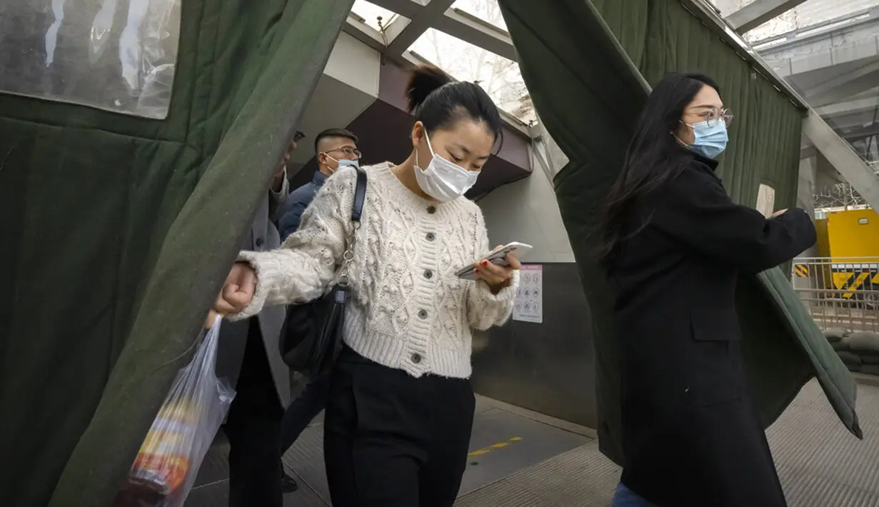 Para komuter yang mengenakan masker untuk melindungi diri dari COVID-19 berjalan keluar dari stasiun kereta bawah tanah di Beijing, China, Rabu (15/12/2021). China mendeteksi kasus kedua varian omicron pada seorang pria berusia 67 tahun. (AP Photo/Mark Schiefelbein)