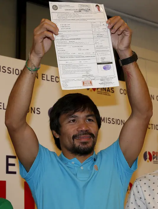 Manny Pacquiao mengangkat Sertifikat Pencalonan Senator  dirinya di Mei 2016 pemilihan nasional, di Komisi Pemilihan Umum, Manila, Filipina (16/10/2015). Pacquiao ditemani istrinya Jinkee dan anaknya Michael. (REUTERS/Erik De Castro)