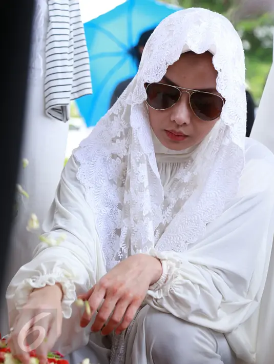 Presenter Terry Putri saat menyiram air dan menaburkan bunga di pemakaman ibunya di TPU Tanah Kusir‎, Jakarta, Minggu (5/2). (Liputan6.com/Herman Zakharia)