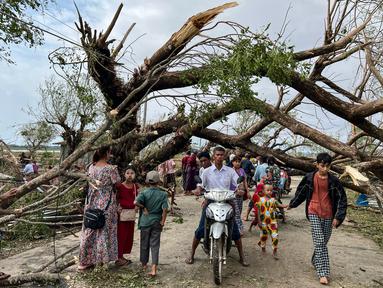 Warga berjalan melewati pohon tumbang setelah Topan Mocha mendarat di Kyauktaw di negara bagian Rakhine Myanmar, Senin (15/5/2023). (Photo by Sai Aung MAIN / AFP)