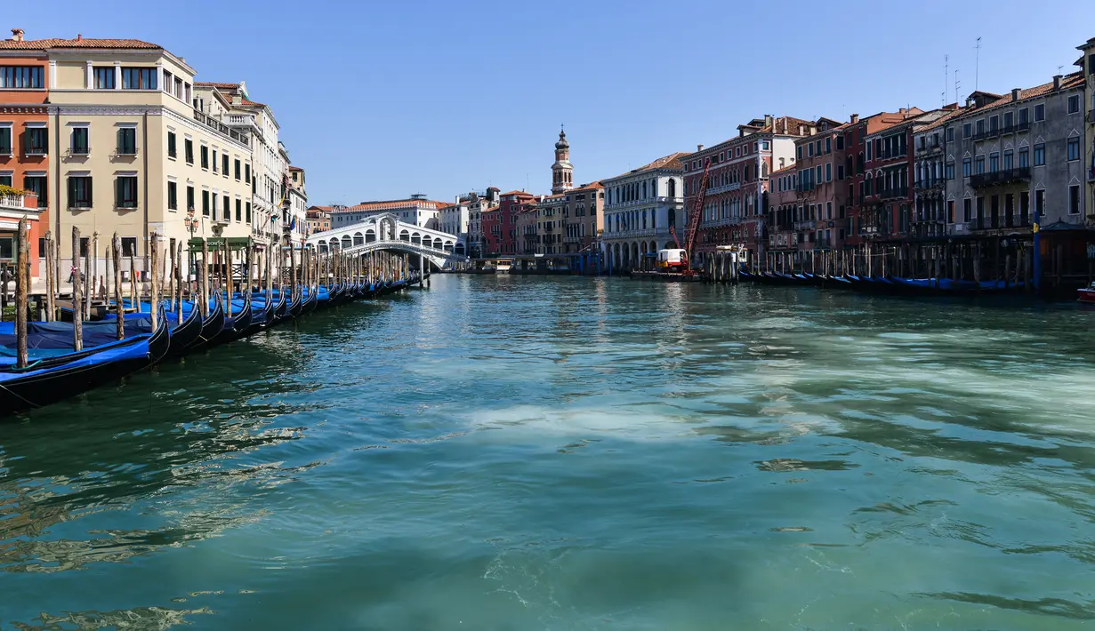Pandangan umum menunjukkan perairan yang lebih jernih Grand Canal di dekat Jembatan Rialto di Venesia pada 18 Maret 2020, . Sejak Italia memberlakukan lockdown akibat pandemi virus corona, air di Kanal Venesia yang biasanya keruh dan gelap berubah menjadi jernih. (ANDREA PATTARO / AFP)