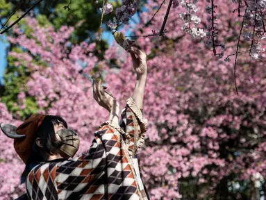 Seorang perempuan muda mengambil foto boneka saat orang-orang keluar ke Taman Ueno untuk melihat bunga sakura awal di Tokyo pada 14 Maret 2023. Pengunjung taman Ueno di Tokyo menikmati bunga sakura yang mekar lebih awal dari biasanya pada musim ini.  (Photo by Richard A. Brooks / AFP)