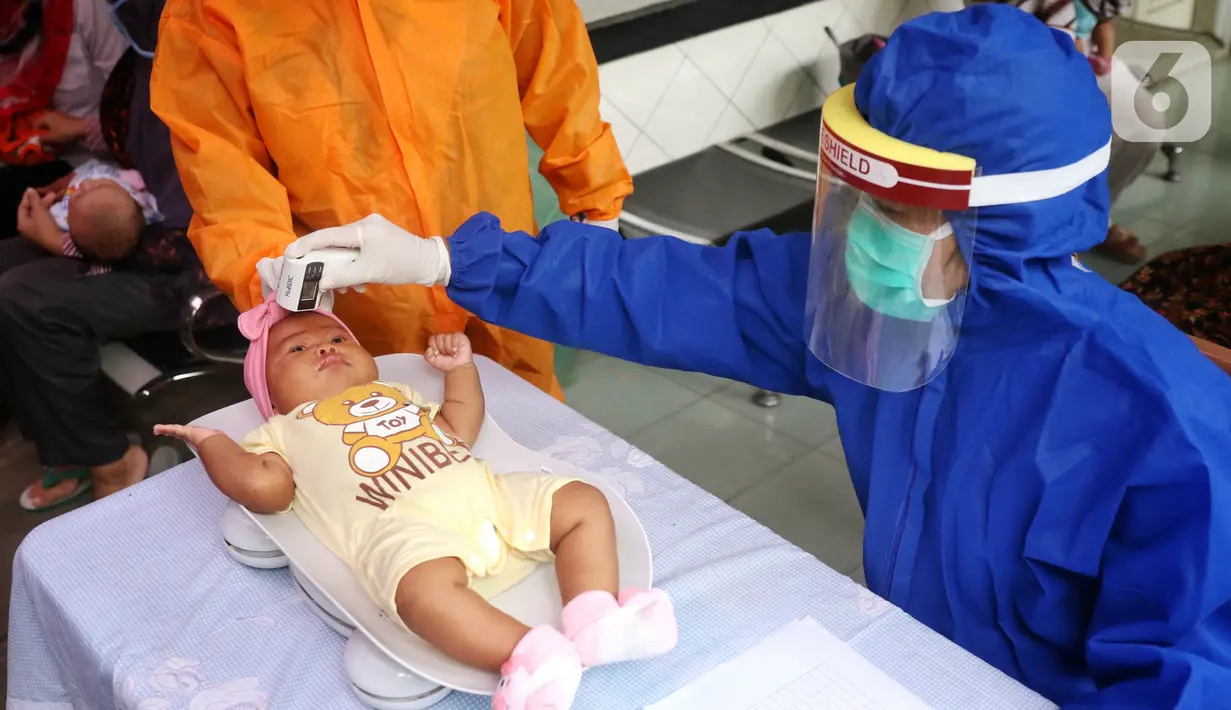 Bidan mengenakan alat pelindung diri (APD) saat melakukan imunisasi kepada bayi di Puskesmas Karawaci Baru, Tangerang, Banten, Rabu (13/5/2020). Pelayanan imunisai sesuai jadwal ini diberikan kepada bayi untuk menambah kekebalan imun tubuh. (Liputan6.com/Angga Yuniar)