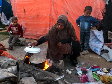 Seorang wanita memasak di sebuah kamp untuk pengungsi Palestina di Khan Yunis, di Jalur Gaza selatan pada 29 Desember 2024. (BASHAR TALEB/AFP)