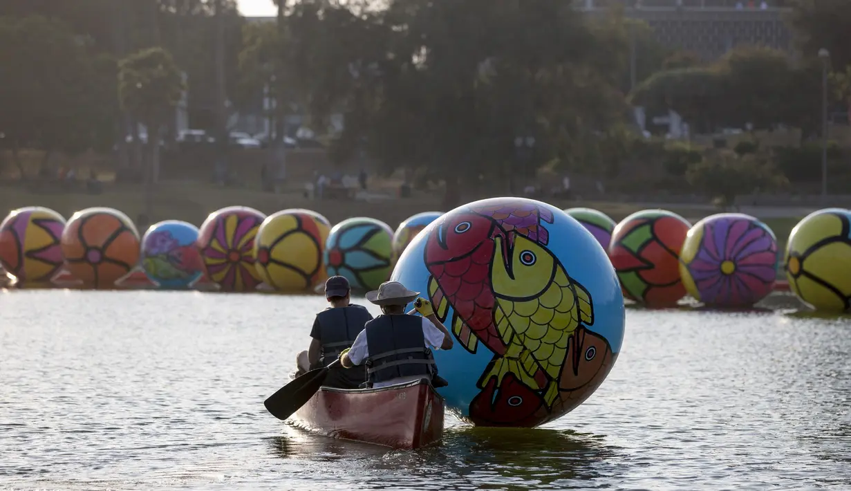 Relawan mengangkut bola raksasa ke danau MacArthur Park selama pameran "Spheres" di Los Angeles, California, AS (21/8/2015). Acara ini menampilkan sekitar 3.000 bola raksasa yang dihias oleh para relawan. (REUTERS/Mario Anzuoni)