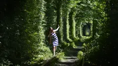 Seorang gadis berjalan di sepanjang bekas rel kereta api atau disebut 'Tunnel of Love' yang dikelilingi pohon dekat desa Ukraina Klevan, Rivno, (6/8). Terowongan cinta yang panjangnya sekitar lima km adalah fenomena botani. (AFP Photo/Sergei Supinsky)