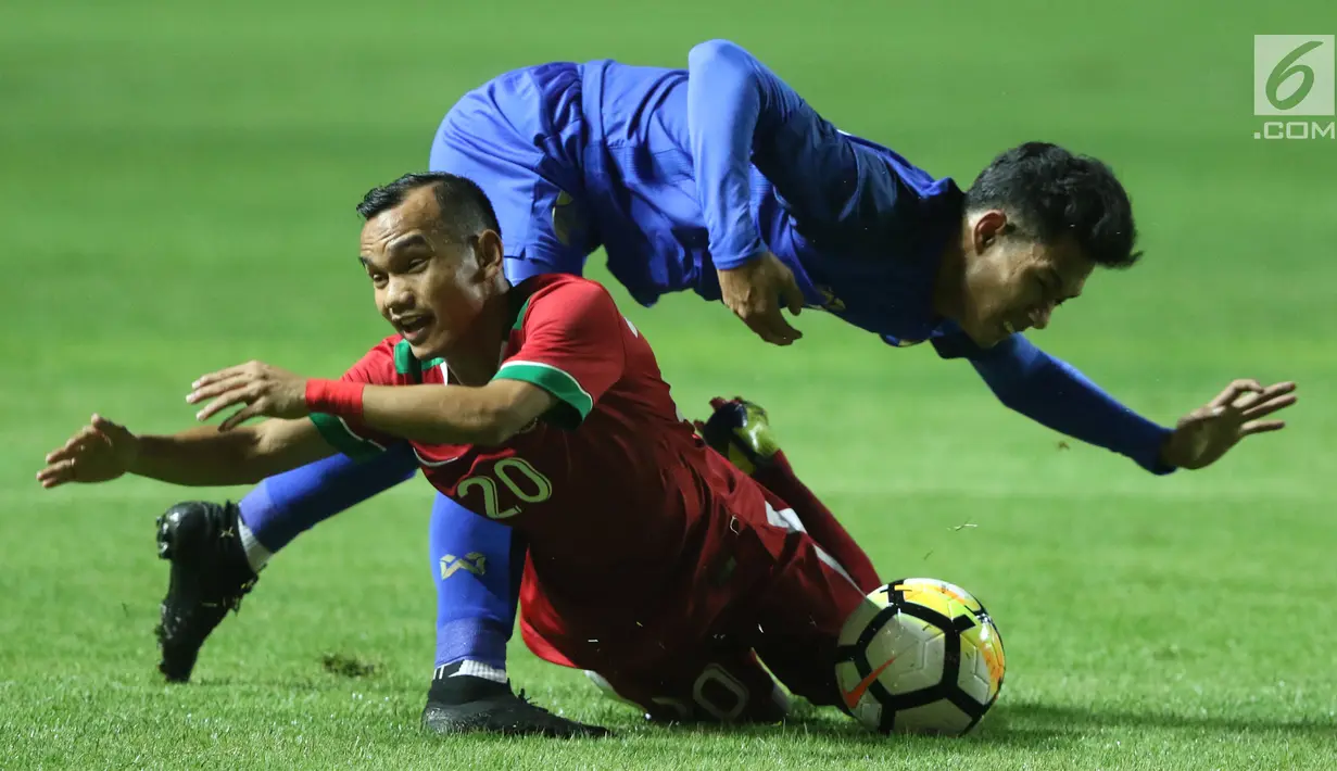 Pemain sayap Timnas Indonesia U-23, Riko Simanjuntak (bawah) berebut bola dengan pemain Thailand U-23, Chaiyawat Buran pada laga persahabatan di Stadion Pakansari, Kab Bogor, Minggu (3/6). Laga berakhir imbang 0-0. (Liputan6.com/Helmi Fithriansyah)