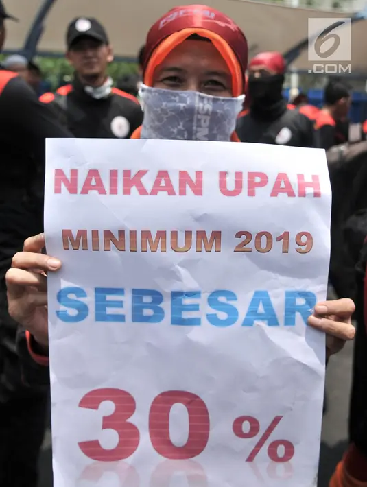 Seorang buruh membawa poster berisi tuntutan kenaikan upah sebesar 30 persen saat menggelar unjuk rasa di depan Gedung Ketenagakerjaan, Jakarta, Rabu (24/10). (Merdeka.com/Iqbal S. Nugroho)