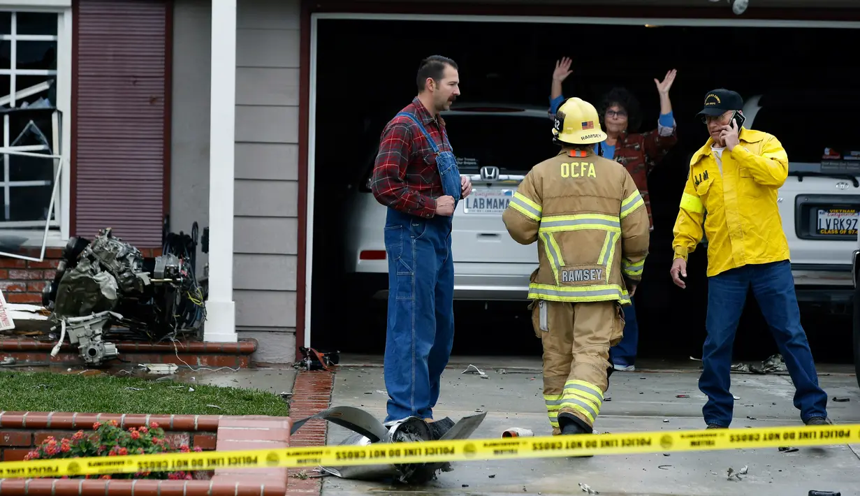 Petugas pemadam kebakaran dan warga saat berada di lokasi kecelakaan pesawat di sebuah rumah di Yorba Linda, California (3/2).Pesawat Cessna 414A jatuh di Yorba Linda tak lama setelah lepas landas dari Bandara Fullerton Municipal. (AP Photo/Alex Gallardo)