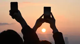 Menyaksikan detik-detik matahari terbenam atau sunset terakhir di tahun 2023 menjadi keasyikan tersendiri bagi sebagian warga. (Jung Yeon-je / AFP)