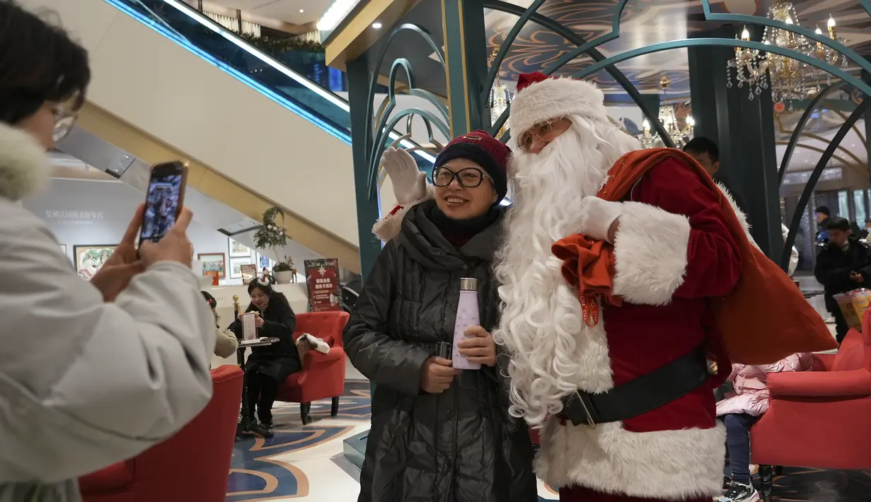 Seorang perempuan berpose untuk foto kenang-kenangan bersama Sinterklas di sebuah pusat perbelanjaan di Shanghai pada 17 Desember 2023. (AP Photo/Wayne Zhang)