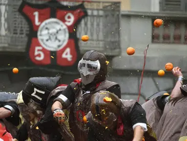 Sejumlah orang yang mengenakan helm melemparkan jeruk kepada warga sebagai bagian dari tradisi "perang jeruk" yang diselenggarakan selama Karnaval Ivrea di Turin, Italia (16/2). (AFP PHOTO/Olivier MORIN)