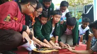 Para siswa SMPN 1 Kota Cirebon mencoba memukul gitar gawai karya anak bangsa yang mendunia (Liputan6,com / Panji Prayitno)