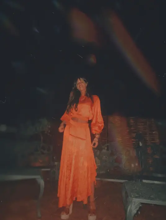 Sara Carbonero mengenakan two piece set bohemian look berwarna orange. Set ini terdiri dari puffy sleeve crop top dan rok asimetris berwarna senada. (instagram/saracarbonero)