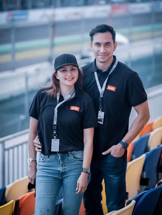 Pasangan selebritis Donna Agnesia dan Darius Sinathrya tengah menyaksikan secara langsung MotoGP di Mandalika. Keduanya tampil kompak kenakan polo shirt warna hitam dan baseball hat. (Instagram/dagnesia).