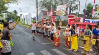 Anak-anak sekolah SD 5 Pering, Gianyar, menjadi penyemangat para pelari Maybank Marathon 2024 di Gianyar, Bali, Minggu (25/8/2024). (Bola.com/Yus Mei Sawitri)