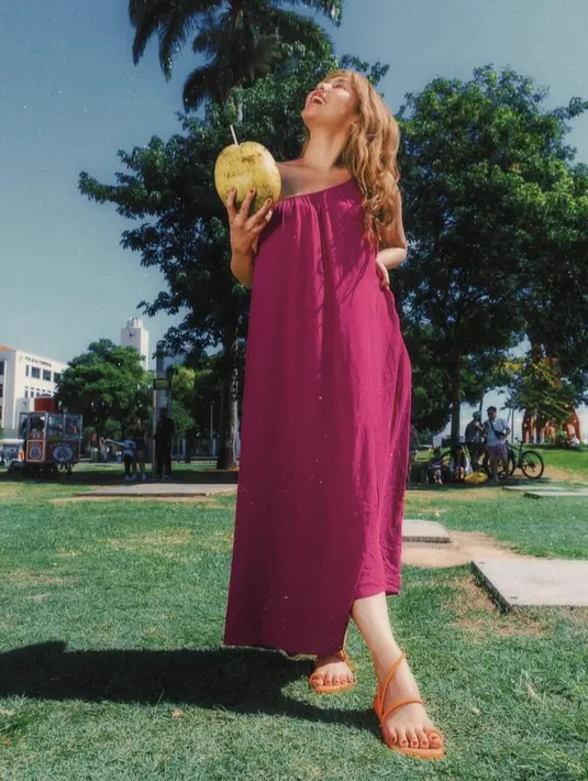 Vanesha juga mengenakan dress one shoulder warna fushcia yang dipadukan dengan sandal orange bertalinya.  Credit: Havaianas