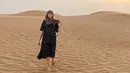 <p>Berada di gurun pasir, Yasmine Wildblood tampil mengenakan dress hitam bercorak lengan 3/4. (@yaswildblood)</p>