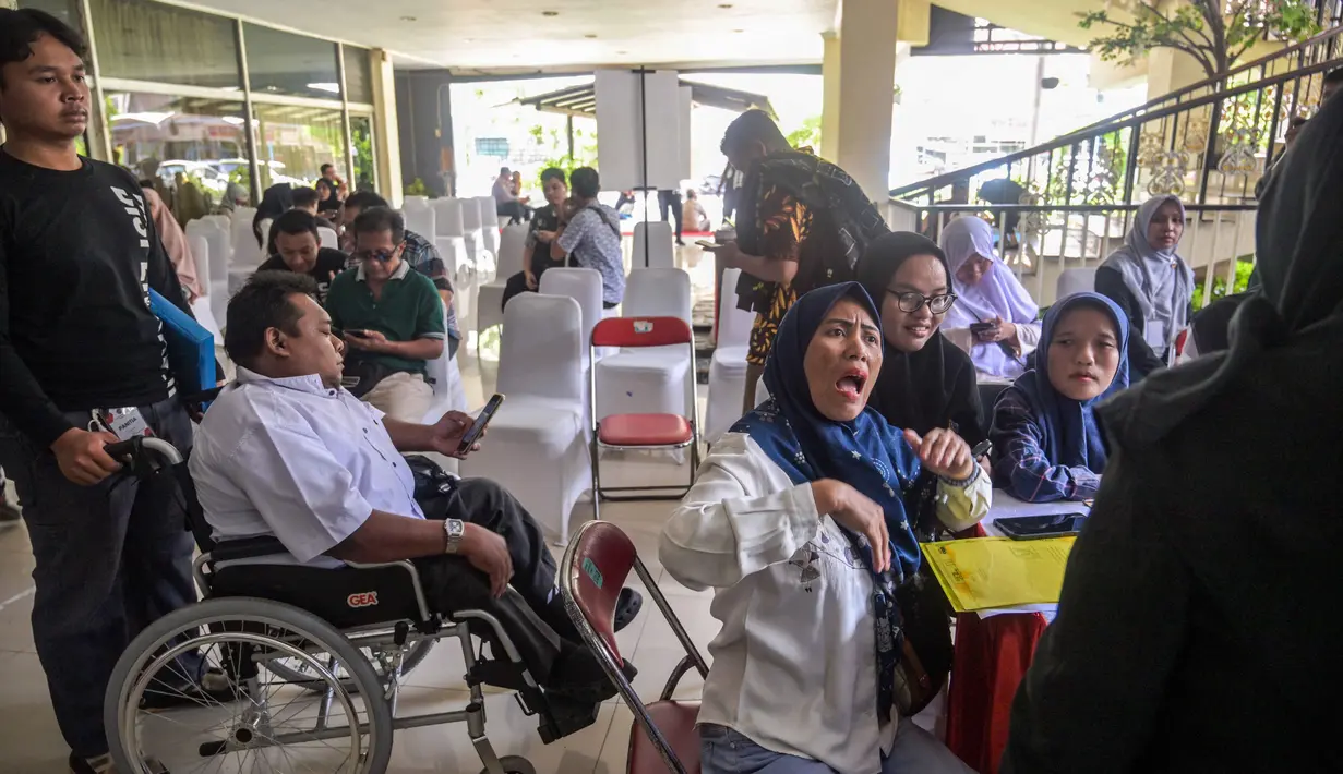 Penyelenggara berharap bursa kerja ini mampu menjangkau sekitar 7.000 penyandang disabilitas. Tampak dalam foto, para penyandang disabilitas menunggu untuk menyerahkan formulir lamaran mereka dalam bursa kerja yang diselenggarakan pemerintah daerah di Surabaya, Jawa Timur, pada Selasa 25 November 2025. (JUNI KRISWANTO/AFP)