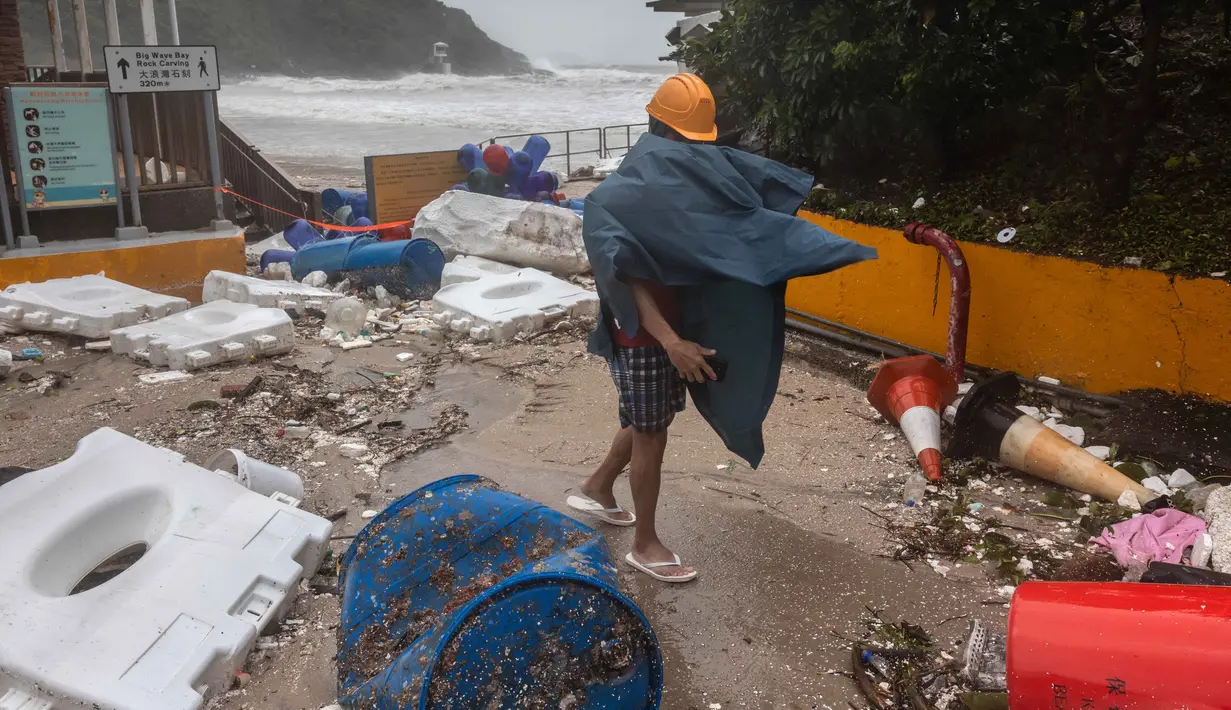 Seorang pria berjalan melewati puing-puing yang tersisa di pantai saat Topan Super Ragasa melintas di Hong Kong pada 24 September 2025. (Dale DE LA REY/AFP)