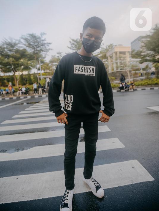 Seorang remaja mengenakanmasker berpose di zebra cross di Taman Sudirman, Jakarta, Rabu (6/7/2022). Tempat ini viral karena jadi ajang adu fashion anak Citayam, Bekasi hingga Bojong Gede. Mereka mengenakan kemeja flanel oversize, celana model 90-an seperti boot cut atau cutbray, sneakers klasik, dan tentu saja topi. (Liputan6.com/Faizal Fanani)
