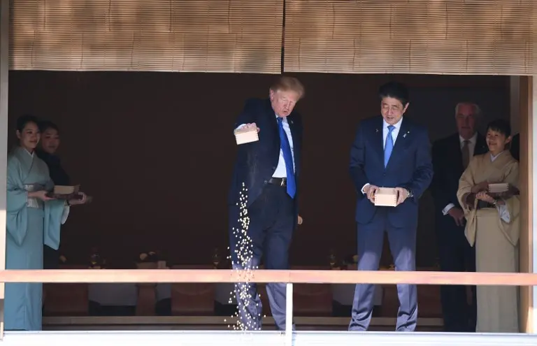 Donald Trump memberi makan koi sebagai salah satu tradisi menyambut tamu di Jepang (JIM WATSON / AFP)