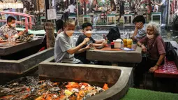 Pengunjung memberi makan ikan mas di restoran bertema ikan di Chiang Mai, Thailand, Selasa (12/4/2022). (Jack TAYLOR/AFP)