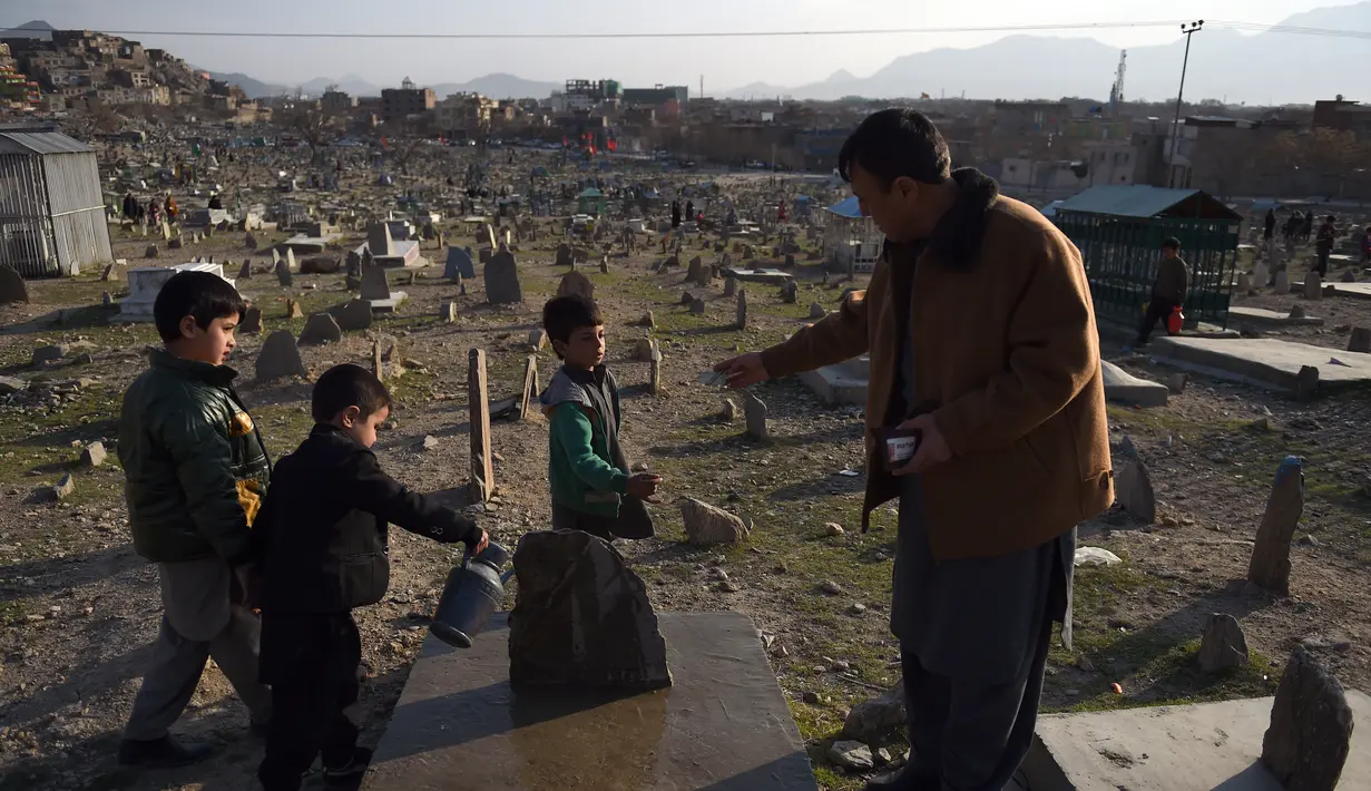 Afghan Zilgai (9) mendapat bayaran setelah menyiram makam kerabat dari seorang peziarah di pemakaman Kart-e-Sakhi, Kabul, 20 Februari 2016. Anak sulung dari 8 bersaudara itu menjual air dari fajar hingga senja kepada para peziarah (AFP PHOTO/Wakil KOHSAR)
