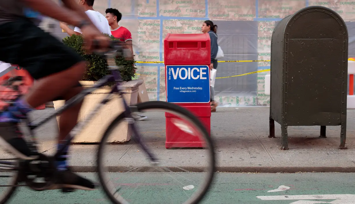 Orang-orang melintas di dekat kotak surat kabar Village Voice yang berada di Manhattan, AS (22/8). Surat kabar Village Voice mengumumkan bahwa mereka tidak lagi menerbitkan edisi cetak. (Drew Angerer/Getty Images/AFP)
