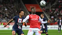 Bek Paris Saint-Germain (PSG) Marquinhos berebut bola dengan pemain depan Reims, Folarin Balogun dalam pertandingan pekan ke-10 Liga Prancis di Stade Auguste-Delaune II, Minggu (9/10/2022) dini hari WIB. Pertandingan berakhir dengan serangkaian pelanggaran karena laga berjalan panas. (AP Photo/Michel Euler)